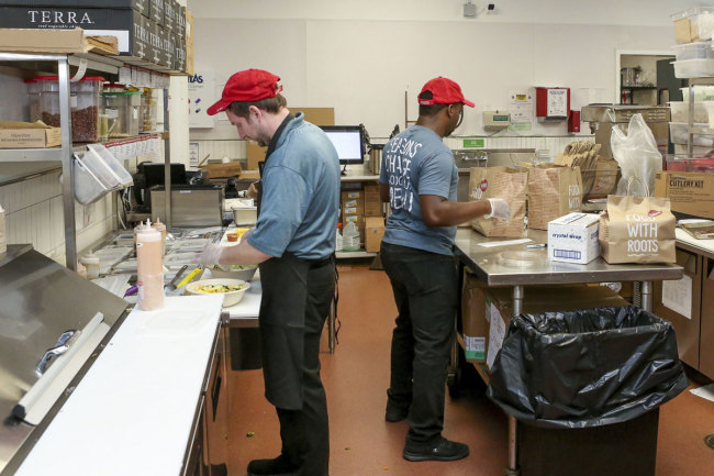 William Burns, left, general manager of the B.Good ghost kitchen inside Kitchen United's Chicago, Ill., location prepares food for delivery on Aug. 29, 2019. [Photo: AP]