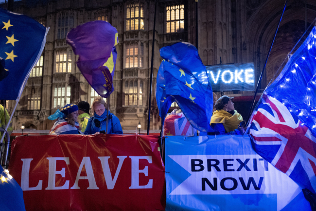 Pro and anti-Brexit protesters wave flags and hold banners as they demonstrate outside of the Houses of Parliament in central London on October 21, 2019. [Photo: AFP/Tolga Akmen]