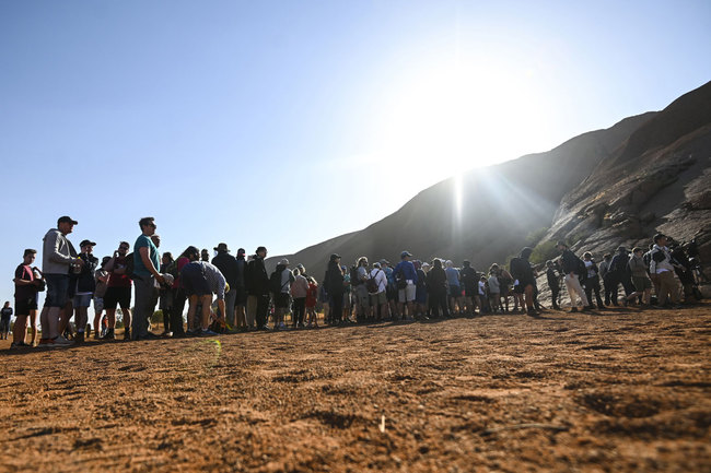 Tourists line up waiting to climb the sandstone monolith called Uluru that dominates Australia's arid center at Uluru-Kata Tjuta National Park, Friday, Oct. 25, 2019, the last day climbing is allowed. [Photo: AP]