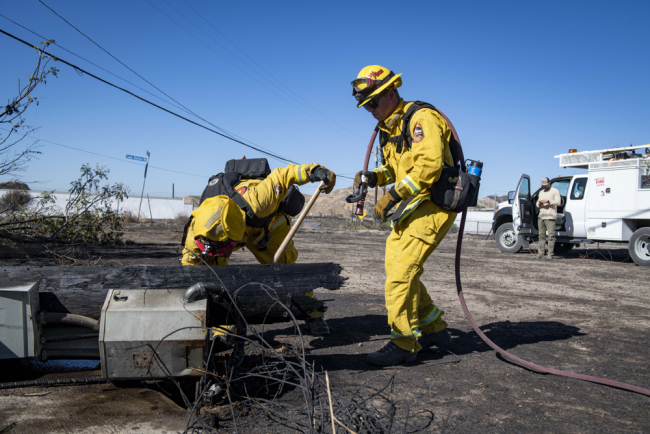 Firefighters with Cal Fire examine a burned down low voltage power pole during the Tick Fire, Thursday, Oct. 25, 2019, in Santa Clarita, California. [Photo: AP/Christian Monterrosa]
