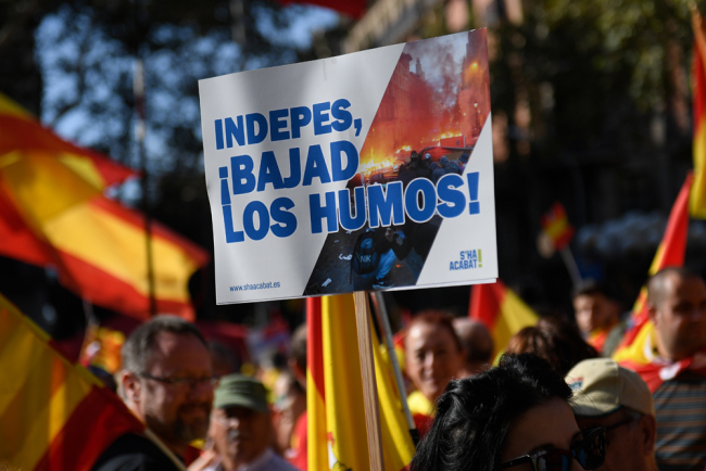 A demonstrator holds a placard reading "separatists, lower the smoke (referring to recent protests)" during a demonstration called by the anti-separatists organisation "Societat Civil Catalana" (Catalan Civil Society, SCC), in Barcelona, on October 27, 2019. [Photo: AFP/Josep Lago]