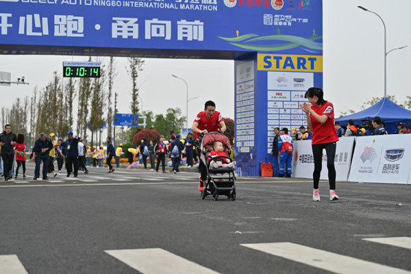 The photo taken on Oct 26, 2019 shows an eight-month-old baby, the youngest participant at the Ningbo International Marathon, taking part in a mini-marathon race in a trolley with his parents. [Photo provided to China Plus]