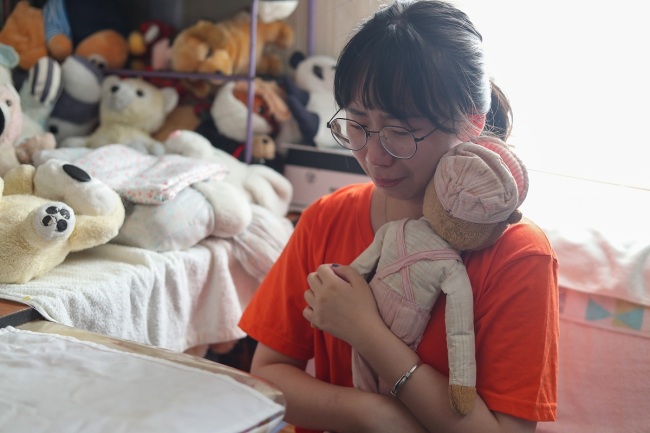 A university student says goodbye to her toy which needs to be repaired at the toy hospital in Shanghai. [Photo: IC]