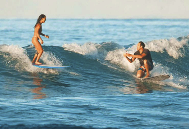 In this Sunday, Nov. 10, 2019 photo, instead of just hanging ten when surfing with his girlfriend, Chris Garth drops to one knee and proposes to Lauren Oiye in the surf off Queen's Beach in Waikiki in Honolulu. [Photo: Tommy Pierucki via AP]