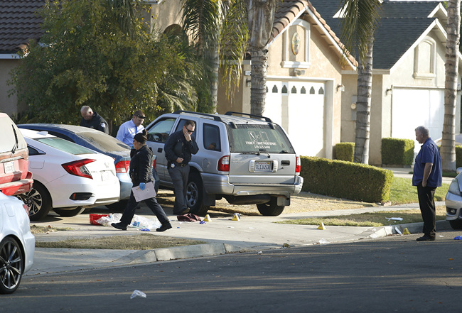 Fresno police investigators work the driveway where a shooting took place at a house party which involved multiple fatalities and injuries in Fresno, Calif., Monday, Nov. 18, 2019. [Photo: AP/Gary Kazanjian]