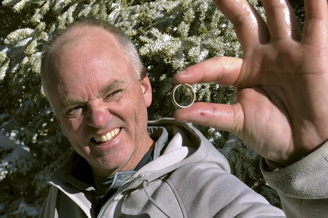 In this Nov. 23, 2019, photo provided by Brendan Cheever, Tom Gately holds a gold wedding band he found by using a metal detector on snow-covered Mount Hancock in New Hampshire's White Mountains. [Photo: Brendan Cheever via AP]