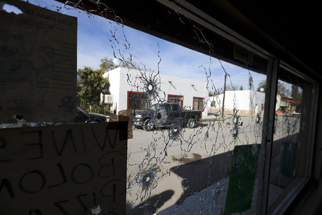 A shop's windows are riddled with bullet holes near City Hall after a gunbattle in Villa Union, Mexico, Monday, Dec. 2, 2019. [Photo: AP]