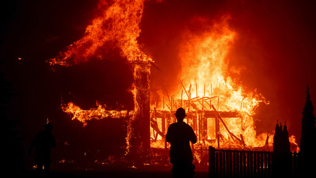 In this Nov. 8, 2018 file photo, a home burns as a wildfire called the Camp Fire rages through Paradise, Calif. [File Photo: AP/Noah Berger]