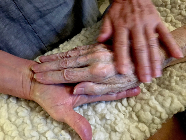 In this 2016 photo provided by Thomas Marrinson, Allison Beach holds the hand of her ailing mother Kathryne Beach inside her home in Hinesburg, Vermont. [Photo: AP/Thomas Marrinson]