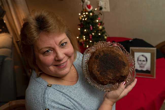 In this Dec. 9, 2019, photo Julie Ruttinger, of Tecumseh, Mich., holds a 141-year-old fruitcake, a family heirloom baked by her great-great-grandmother, Fidelia Ford, in 1878. Fidelia, pictured at left, died before the cake was served and the family, out of respect of her memory, decided not to eat it and has instead passed it down for generations. [Photo: David Guralnick/Detroit News via AP] 