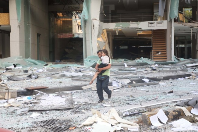 Muž nesoucí dítě jde kolem poškozené budovy po výbuchu v Bejrútu v Libanonu, 4. srpna 2020. / Xinhua