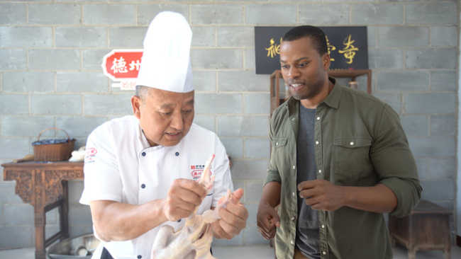 Snímek: Dědicův učeň Cui Ling (Cchuej Ling) ukazuje, jak před vařením umístit kuře do slavné pozice. / fotka CGTN