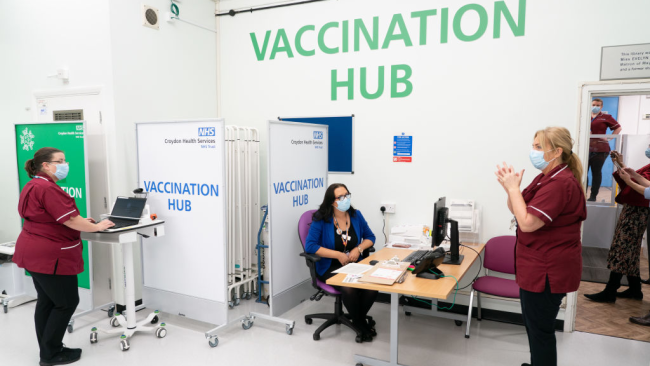Lékaři a zdravotní sestry tleskají poté, co generální ředitelka Covid Recovery, Becky Board, podává první vakcínu Pfizer-BioNTech COVID-19 v Londýně pacientovi Georgi Dyerovi (90 let) v nemocnici Croydon University Hospital, na začátku dosud největšího imunizačního programu v historii ve Velké Británii v Londýně, Velká Británie, 8. prosince 2020. / Getty Images