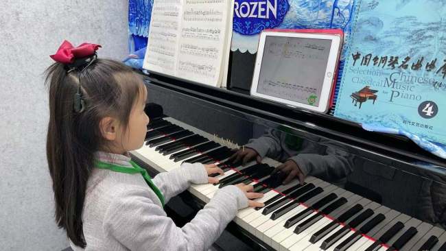 Sedmiletá dívka ze Šanghaje se učí hrát na klavír pomocí nástroje pro online výuku klavíru s podporou AI.