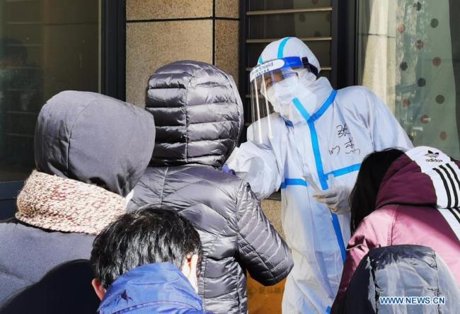 Fotografie pořízená mobilním telefonem ukazuje, jak zdravotničtí pracovníci odebírají vzorky výtěrů od obyvatelů na sídlišti ve čtvrti Qiaoxi v Shijiazhuang, hlavním městě severočínské provincie Hebei, 6. ledna 2021. Shijiazhuang začal ve středu provádět testy nukleových kyselin pokrývající všechny občany. (Xinhua / Yang Zhirun)