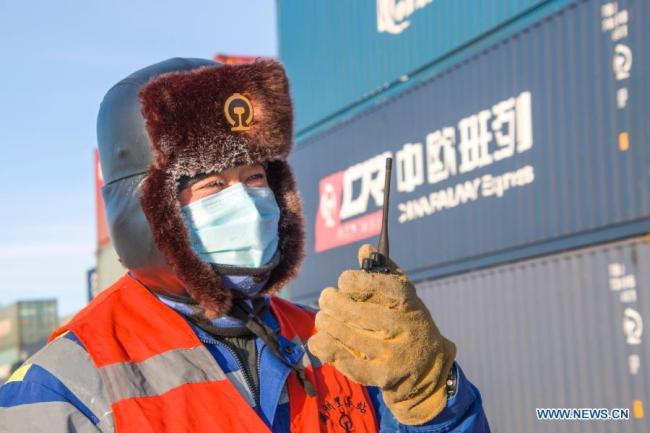 Zaměstnanec hovoří se svým kolegou prostřednictvím přenosné vysílačky v Manzhouli (Man-čou-li) v severočínské autonomní oblasti Vnitřní Mongolsko, 30. prosince 2020. Počet čínsko-evropských nákladních vlaků, které přijíždějí a odjíždějí přes Manzhouli, největší čínský pozemní přístav, dosáhl v roce 2020 rekordu navzdory dopadu COVID-19, uvedly ve středu místní železniční úřady. (Foto: Guo Nailun / Xinhua)