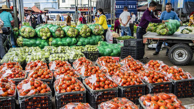 Zemědělci vykládají zeleninu na velkoobchodním trhu Fengxiang (Feng-siang) ve městě Haikou (Chaj-kchou) v jihočínské provincii Hainan (Chaj-nan), 8. února 2021. / CFP