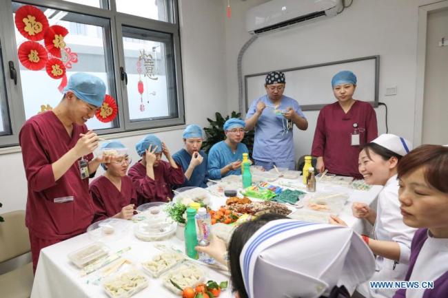 Dobrovolníci a zaměstnanci stavebního projektu ukazují taštičky, které vyrobili ve městě Tangshan (Tchang-šan) v severočínské provincii Hebei (Che-pej), 11. února 2021. Letošní Jarní svátek připadá na pátek. (Xinhua)<br>Zdravotničtí pracovníci z oddělení pohotovosti jedí v kanceláři v nemocnici Peking Union Medical College Hospital, v Pekingu, hlavním městě Číny, 11. února 2021. Letošní Jarní svátek připadá na pátek. (Xinhua / Zhang Yuwei)