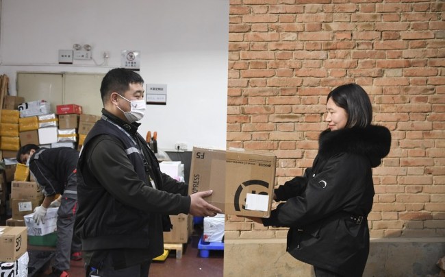 Kombinovaná fotografie ukazuje Nie Huachen (Nie Chua-čchen), který drží balíček na svém pracovním místě v obvodě Futian (Fu-tchien) ve městě Shenzhen (Šen-čen) v jičínské provincii Guangdong (Kuang-tung), 10. února 2021 (vlevo) a jeho manželku, která dostává balíček v okrese Tongxu (Tchung-sü) v provincii Henan (Che-nan) v centrální Číně, 10. února 2021 (vpravo, fotografie pořízená Li Jianan).