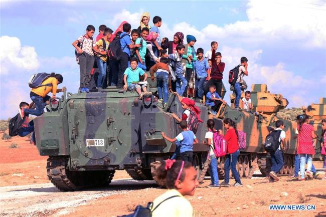  Des enfants sur un véhicule militaire turc, alors qu'un convoi militaire traverse leur village à la frontière turco-syrienne, à Reyhanli, dans la province turque de Hatay, le 11 octobre 2017. Les troupes turques ont franchi dimanche la frontière pour entrer dans la province syrienne d'Idlib, afin d'y mener une mission de reconnaissance, ont annoncé lundi les forces armées turques. (Photo : Xinhua)
