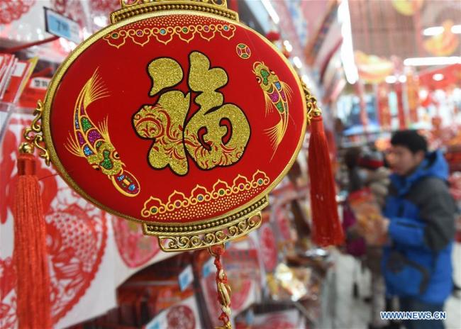Des personnes sélectionnent des articles de décoration pour la Fête du printemps, dans la ville de Qingdao, dans la province du Shandong (est), le 14 janvier 2018. La Fête du printemps, ou Nouvel An lunaire chinois, tombera cette année le 16 février. (Phto : Li Ziheng)