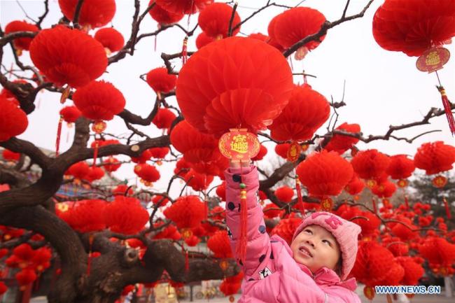 Une enfant attrape une lanterne à la porte sud du parc Ditan, également connu sous le nom de parc du Temple de la Terre, le 27 janvier 2018 à Beijing. (Photo / Xinhua)