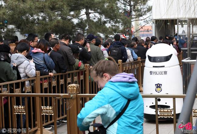 Photo prise le 21 mars, montrant un robot policier travaillant à l’entrée de la place Tian’anmen à Beijing. Il peut se déplacer et rappeler aux visiteurs d'observer l'ordre dans la queue, ce qui facilite grandement le travail des contrôleurs de sécurité. 