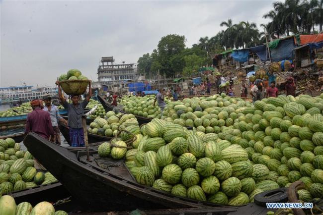 Des ouvriers déchargent des pastèques des bateaux près d'un marché à Dhaka, capitale du Bangladesh, le 21 avril 2018.