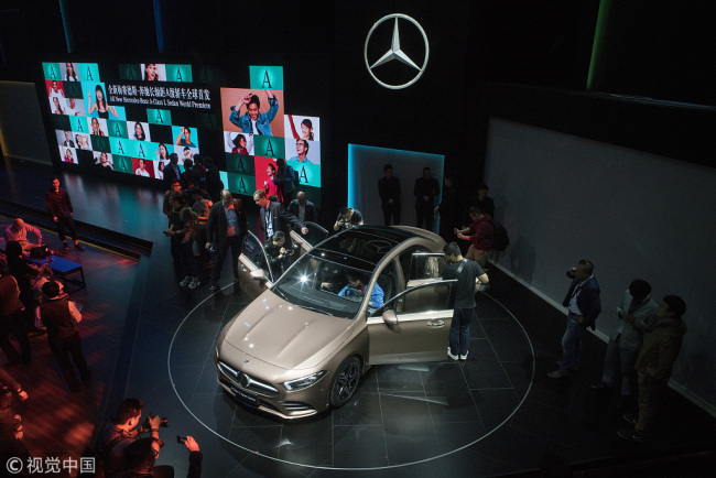 Des visiteurs regardent une nouvelle berline Mercedes-Benz Classe-A lors d'une première au salon Auto China 2018, le 24 avril 2018 à Beijing.