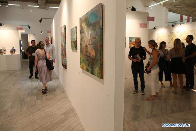 Des visiteurs regardent des oeuvres d'art lors de l'événement Art Athina à Athènes, en Grèce, le 23 juin 2018. L'événement est l'une des plus anciennes foires d'art de l'Europe. (Xinhua/Marios Lolos)