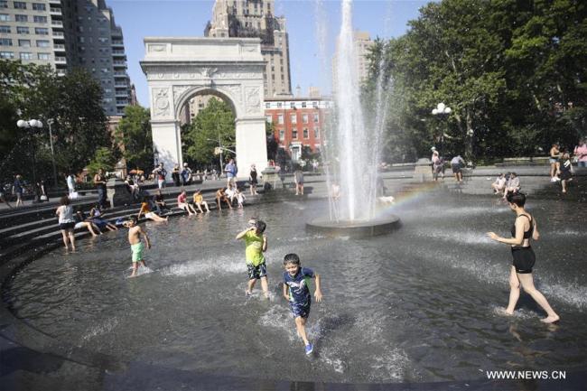 es gens se rafraîchissent dans une fontaine à New York aux Etats-Unis, le 2 juillet 2018. La température a atteint jusqu'à 35 degrés lundi dans la ville américaine. (Photo : Wang Ying)