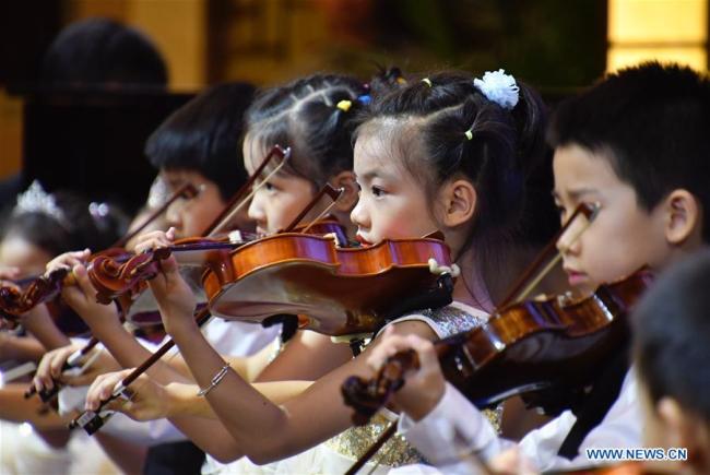 Les enfants d'une troupe artistique chinoise jouent du violon lors d'un concert à Beijing, capitale de la Chine, le 29 juillet 2018. Le concert fait partie des activités de la semaine d'échanges culturels entre adolescents chinois et russes. (Photo : Li Xin)