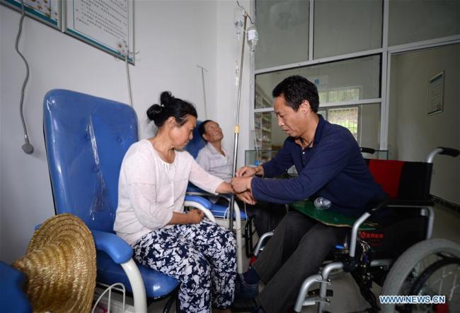 Le docteur Sun Qingyong (à droite) fait une injection intraveineuse à une patiente dans une clinique du village de Shaluo du canton de Guanghuojie, au comté de Ningshan à Ankang, dans la province du Shaanxi (nord-ouest), le 15 août 2018. M. Sun est devenu paraplégique dans un accident de la route il y a 22 ans, mais a rapidement commencé à soigner ses concitoyens en fauteuil roulant. Un grand nombre de praticiens médicaux sont actifs dans les zones rurales chinoises, où les soins de santé sont encore sous-développés. Pratiquant dans des conditions de travail défavorables, ils portent en eux l'esprit humanitaire et se sont consacrés à la santé des citoyens ruraux. La Chine a marqué sa première Journée des travailleurs médicaux le 19 août 2018. 