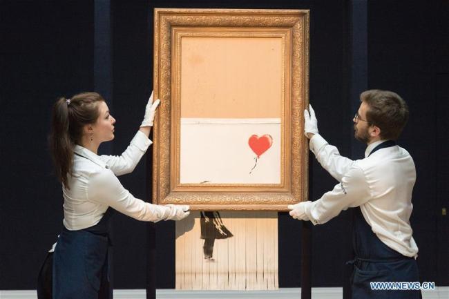 Le personnel de Sotheby's présente « L'amour est dans la poubelle » de Banksy à Londres
