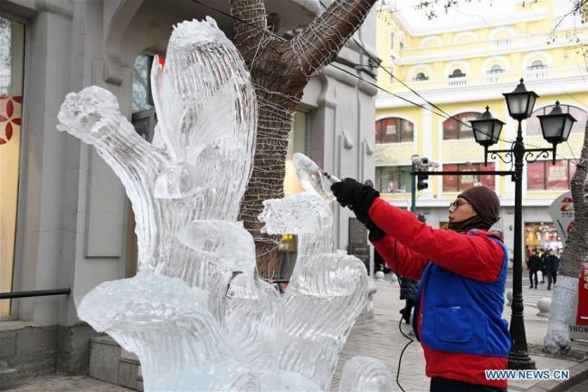 Photo prise le 1er janvier 2019, montrant un sculpteur en train de créer une sculpture de glace sur la rue centrale de Harbin, capitale de la province du Heilongjiang (nord-est de la Chine). Les sculptures de glace sont devenues une attraction très appréciée des touristes pendant les congés du Nouvel An.