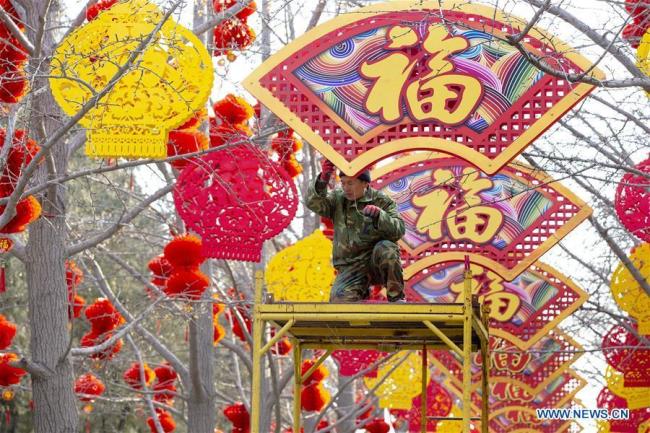 Un ouvrier installe des décorations pour la fête du Printemps au parc Ditan à Beijing, le 26 janvier 2019.