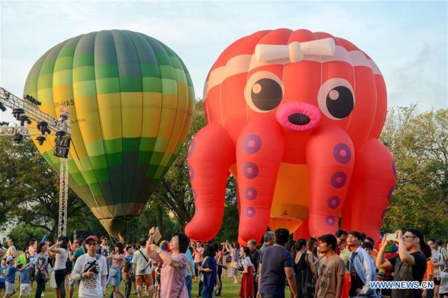 Des gens visitent le Festival des montgolfières à Penang, en Malaisie, le 10 février 2019. De nombreuses montgolfières manipulées par des aérostiers internationaux et locaux sont exposées durant ce festival de deux jours qui s'est ouvert samedi. (Photo : Chong Voon Chung)