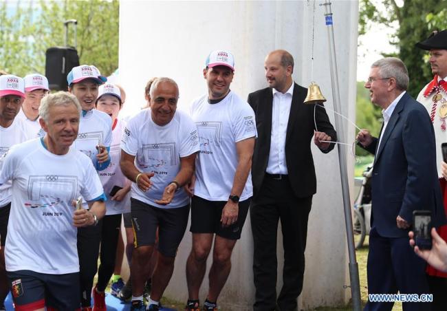 Le président du Comité international olympique (CIO), Thomas Bach (2e à droite), sonne la cloche pour lancer la course de la Journée olympique à Lausanne, en Suisse, le 22 juin 2019.