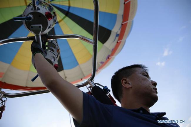 Un homme pilote une montgolfière à l'occasion d'un festival de montgolfières dans le district de Taitung, à Taiwan, dans le sud-est de la Chine, le 25 juillet 2019. Ce festival de montgolfières d'une durée de 45 jours a débuté le 29 juin. (Photo : Wu Lu)