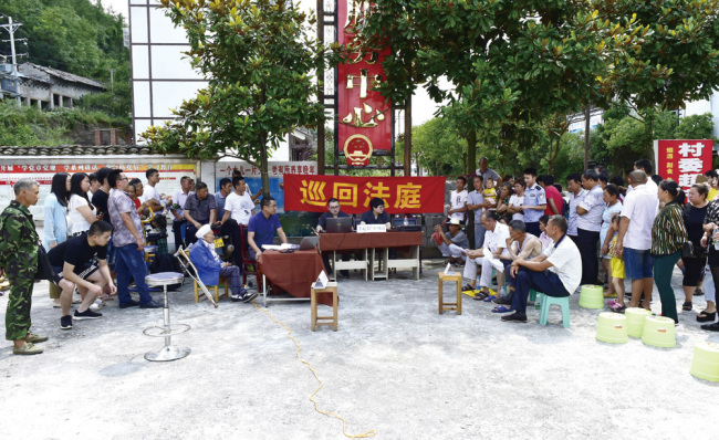 Les juges du tribunal du comté de Yunyang, dans la ville de Chongqing, se rendent le 17 juillet 2018 dans un village ethnique de Tujia, à la campagne, pour résoudre un conflit familial. Le demandeur, 90 ans, vit dans une région montagneuse reculée. (Photo crédit : Nouvelles de la Cour / Qin Hui)