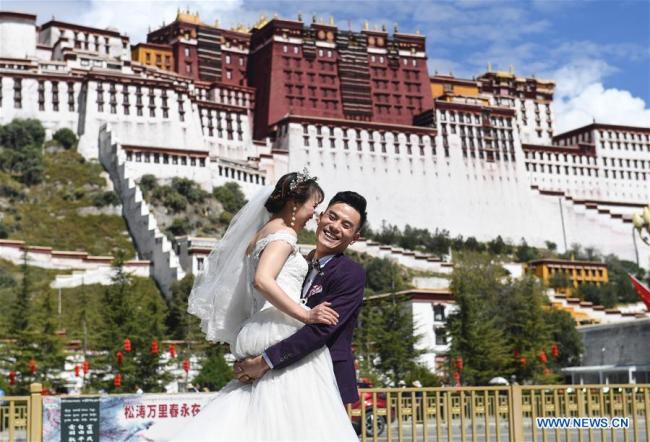 Un couple pose pour des photos de mariage sur la place du Palais du Potala lors des congés de la Fête nationale à Lhassa, capitale de la région autonome du Tibet (sud-ouest de la Chine), le 6 octobre 2019. (Photo / Xinhua)