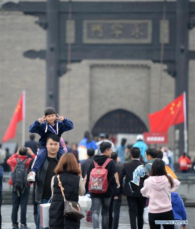 Des touristes prennent des photos devant la porte Yongningmen, porte sud des anciennes murailles de la ville, au cours des vacances de la fête nationale à Xi'an, capitale de la province chinoise du Shaanxi (nord-ouest), le 6 octobre 2019. (Photo : Zhang Bowen)
