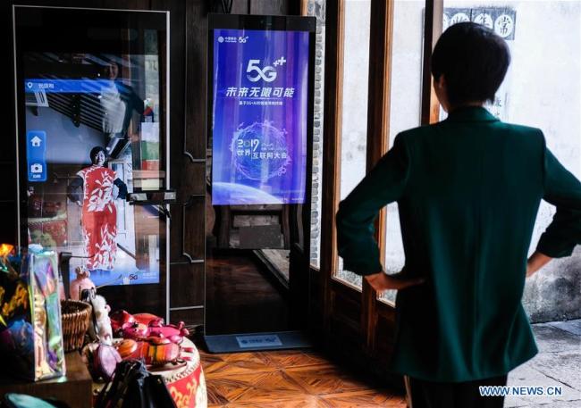 Une visiteuse essaie des vêtements virtuels via un dispositif alimenté par la réalité virtuelle et la 5G dans un magasin de Wuzhen, dans la province du Zhejiang (est de la Chine), le 19 octobre 2019.