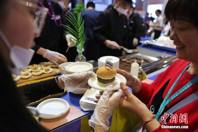 Des visiteurs goûtent des burgers à la viande artificielle, le 6 novembre, à la 2e Foire internationale des importations de Chine.