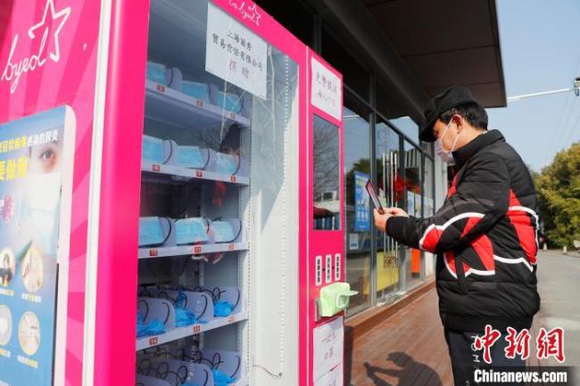 Des résidents en train d’acheter des masquesdistributeur automatique, le 4 février, dans un quartierShanghai.(Photo: Yin Liqin/ChinaNews )