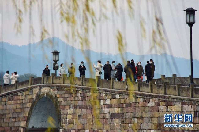 Des touristes sur le pont Duanqiao du lac de l’Ouest, le 19 février, à Hangzhou. (Photo : Zheng Mengyu/Xinhua)