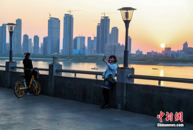 Le 20 mars, une habitante prend un selfie au bord du fleuve Wuchang, à Wuhan. A la fin du jour, la ville radie d’une beauté sereine.