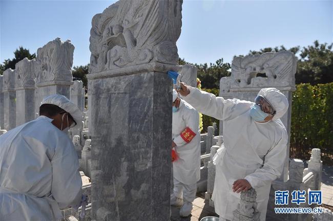 Des employés du cimetière nettoient une tombe à la place de ses clients, le 28 mars, à Beijing.