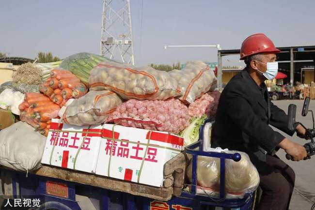 Photos prises le 26 octobre, montrant des habitants en train d’acheter des légumes sur un marché au quartier de Donghu de la préfecture de Kashgar, dans la région autonome ouïghoure du Xinjiang.