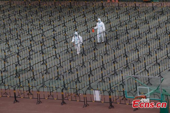 Eργαζόμενοι με προστατευτική στολή ψεκάζουν απολυμαντικό σε δοκιμών στην περιοχή Τσαογιάνγκ, Πεκίνο, πρωτεύουσα της Κίνας, στις 23 Ιουνίου 2020. Ένα δημοτικό σχολείο μετατράπηκε προσωρινά σε έναν τόπο δοκιμών νουκλεϊνικού οξέος για τους κατοίκους της περιοχής. (Φωτογραφία / China News Service)